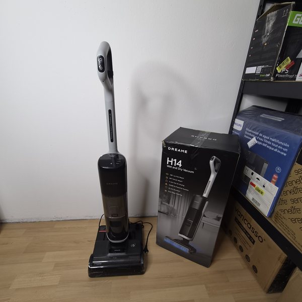 Gerät aufrecht auf der Ladestation, rechts daneben der Originalkarton.