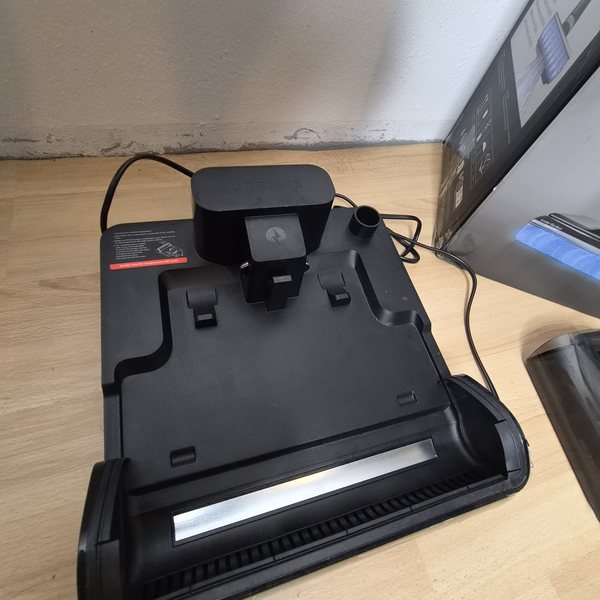 Ladestation von oben — flache schwarze Basis mit Aufnahme für das Gerät.