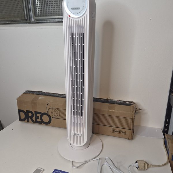 Der Turmventilator aufgebaut, davor Fernbedienung, Kurzanleitung und Netzkabel, dahinter der Originalkarton.