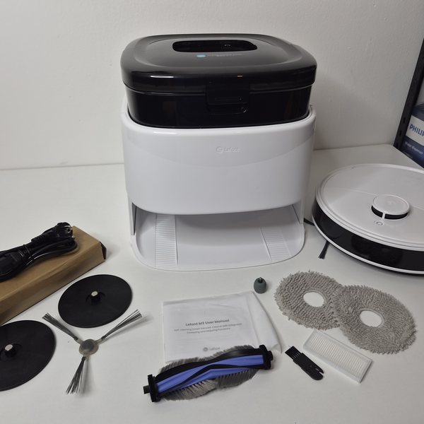Alle Teile ausgelegt: Roboter, Station, Netzkabel, Wischteller, Wischpads, Bürstenwalze, Seitenbürste, HEPA-Filter.