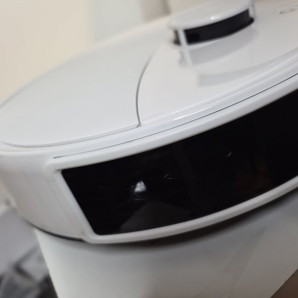 Roboterdeckel und schwarzes Sensorband mit feinen Spuren.