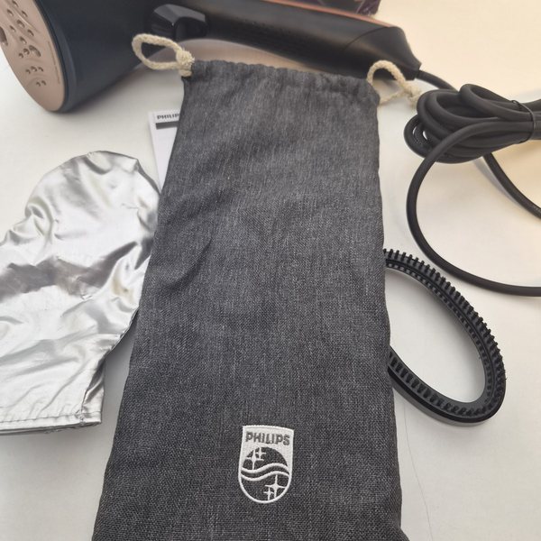 Der graue Aufbewahrungsbeutel mit Philips-Logo, daneben Handschuh und Bürstenaufsatz.