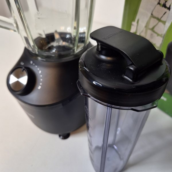 Eine To-Go-Flasche mit Trinkdeckel neben der Motoreinheit.